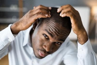 Concerned male looking at scalp to check hair loss